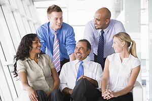 Five businesspeople indoors smiling (high key/selective focus)