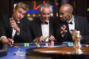 Three men in casino playing roulette and smiling (selective focus)