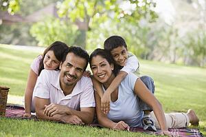 Family outdoors in park with picnic smiling (selective focus)