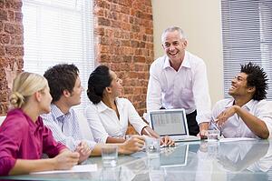 Five businesspeople in boardroom with laptop laughing