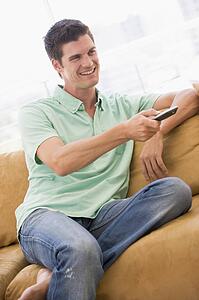 Man in living room with remote control smiling