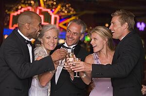 Five people in casino toasting champagne smiling (selective focus)