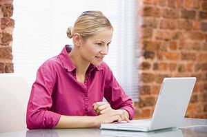 Businesswoman sitting in office using laptop smiling