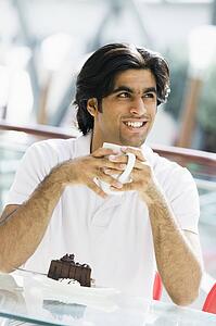 Man at restaurant eating dessert and smiling (selective focus)