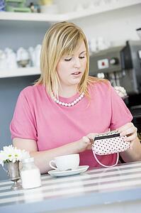 Young woman sitting at a table checking change purse