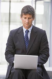 Businessman sitting in office lobby using laptop