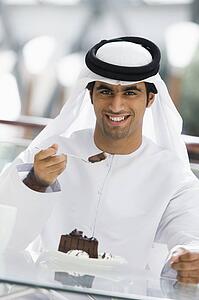 Man at restaurant eating dessert and smiling (selective focus)