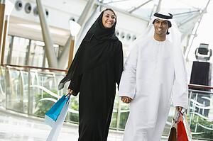 Couple walking in mall holding hands and smiling (selective focus)