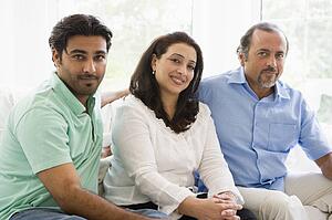 Two men and a woman sitting in living room smiling (high key)