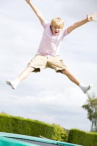 Young boy jumping on trampoline smiling