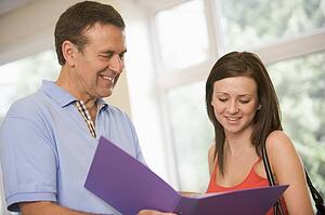 Teacher in corridor talking to student with notebooks