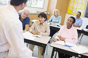 Adult students in class with teacher (selective focus)