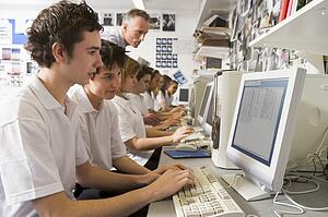 Students working on computer workstations with teacher