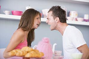 Young couple sitting at a table arguing