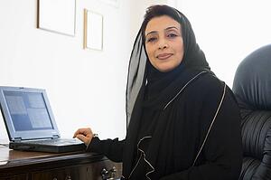Woman in office with laptop smiling (high key/selective focus)