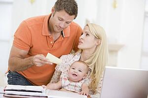 Couple and baby in dining room with laptop and paperwork