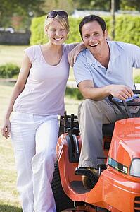 Couple outdoors with lawnmower smiling