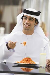 Man at restaurant eating spaghetti and smiling (selective focus)