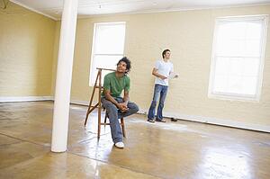 Two men with ladder in empty space holding paper and thinking