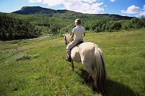 Woman outdoors riding horse in scenic location