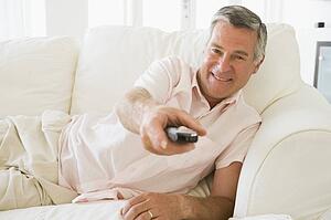 Man in living room using remote control smiling