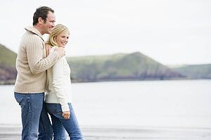 Couple standing on beach smiling