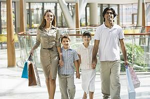 Family walking in mall holding hands and smiling (selective focus)