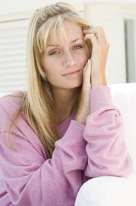Blonde woman in a pink sweater posing outdoors
