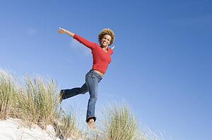 Young woman jumping on a sand hill