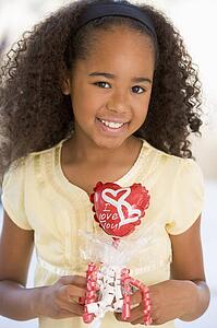 Young girl on Valentine's Day holding love themed balloon smiling