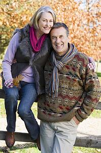 Couple outdoors in park by fence smiling (selective focus)