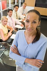 Businesswoman with four businesspeople at boardroom table in background