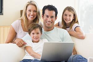 Family in living room with laptop smiling