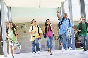 Six students running away from front door of school excited