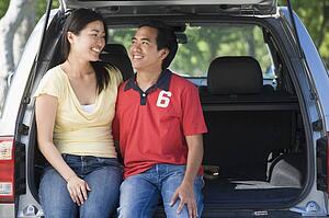Couple sitting in back of van smiling