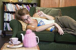 Young woman lying on sofa at home eating potato chips