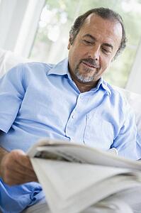 Man in living room with newspaper (high key/selective focus)