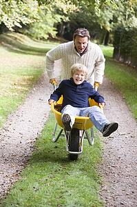 Father pushing son in wheelbarrow