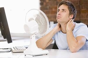 Businessman in office with computer and fan cooling off