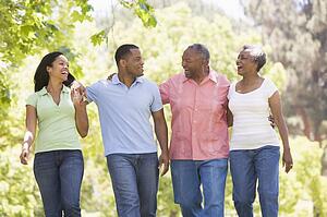 Two couples walking outdoors arm in arm smiling