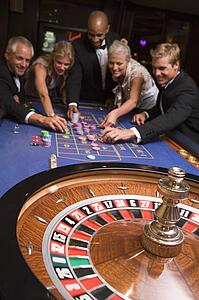 Group of people in casino playing roulette and smiling (selective focus)