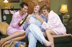 Three woman in night clothes sitting at home drinking wine
