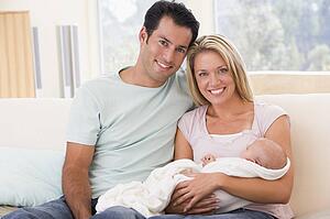 Couple in living room with baby smiling