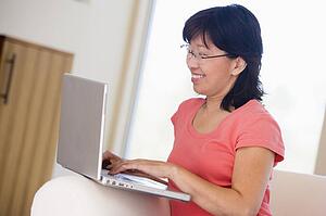 Woman in living room with laptop smiling