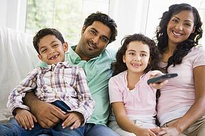 Family in living room with remote control smiling (high key/selective focus)