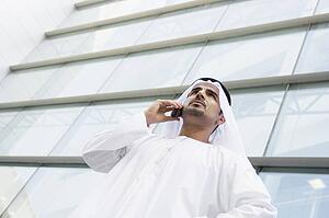 Businessman standing outdoors by building on cellular phone (selective focus)