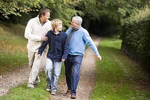 Two men and young boy walking on path outdoors smiling (selective focus)
