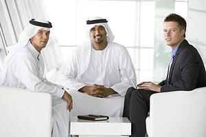Three businessmen indoors with a laptop smiling (high key/selective focus)