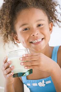 Young girl indoors drinking milk smiling