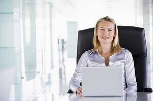 Businesswoman sitting in office with laptop smiling